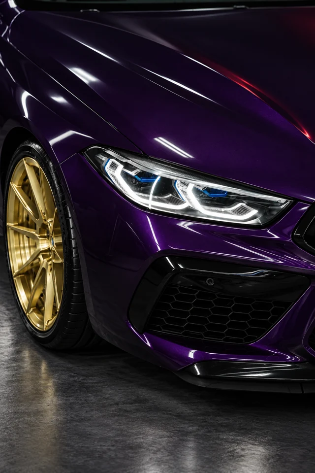 Крупный план фары, фиолетового кузова и золотого диска BMW